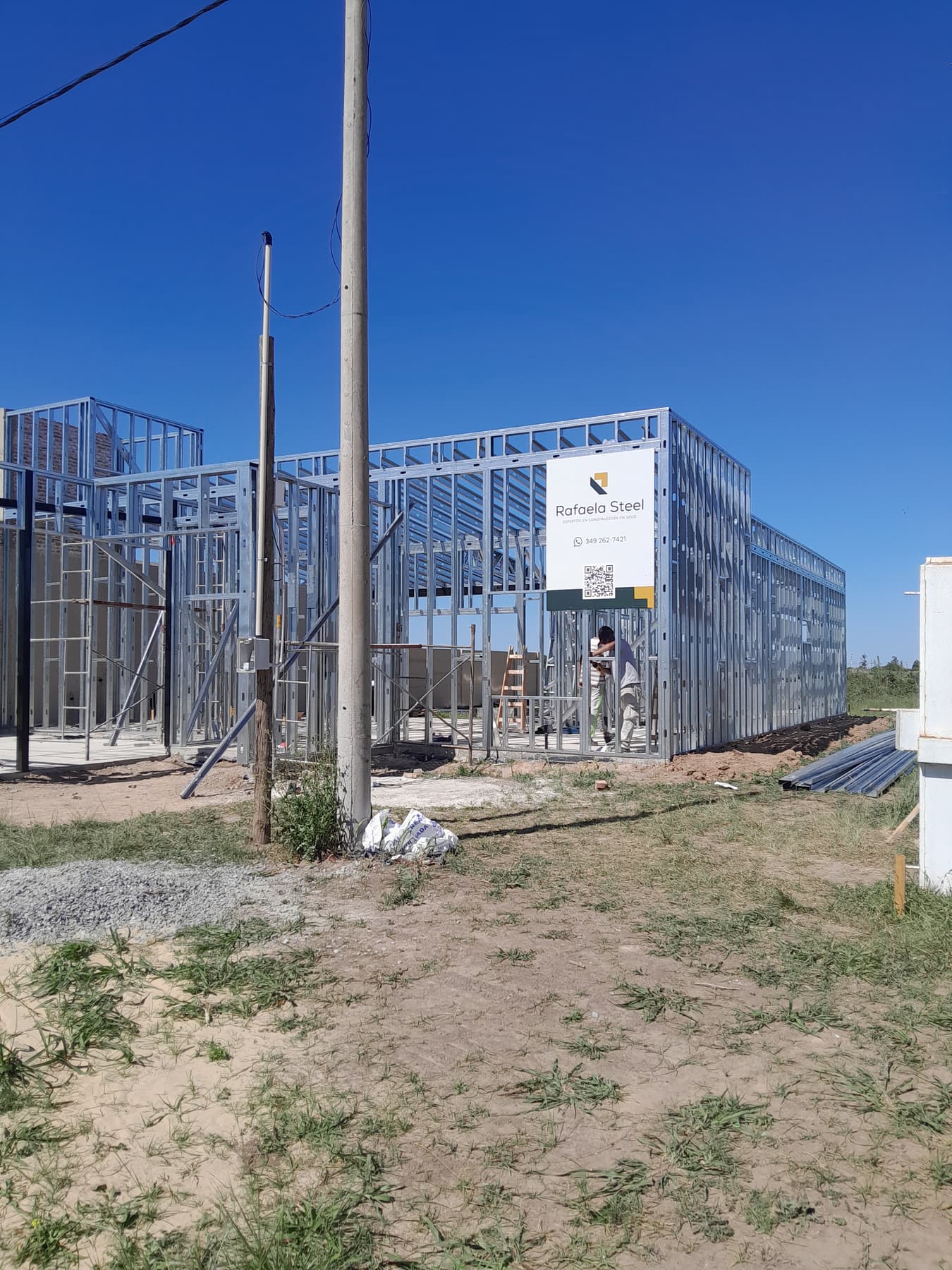 Estructura de perfiles de acero galvanizado de una vivienda en montaje, con el cartel de obra de Rafaela Steel